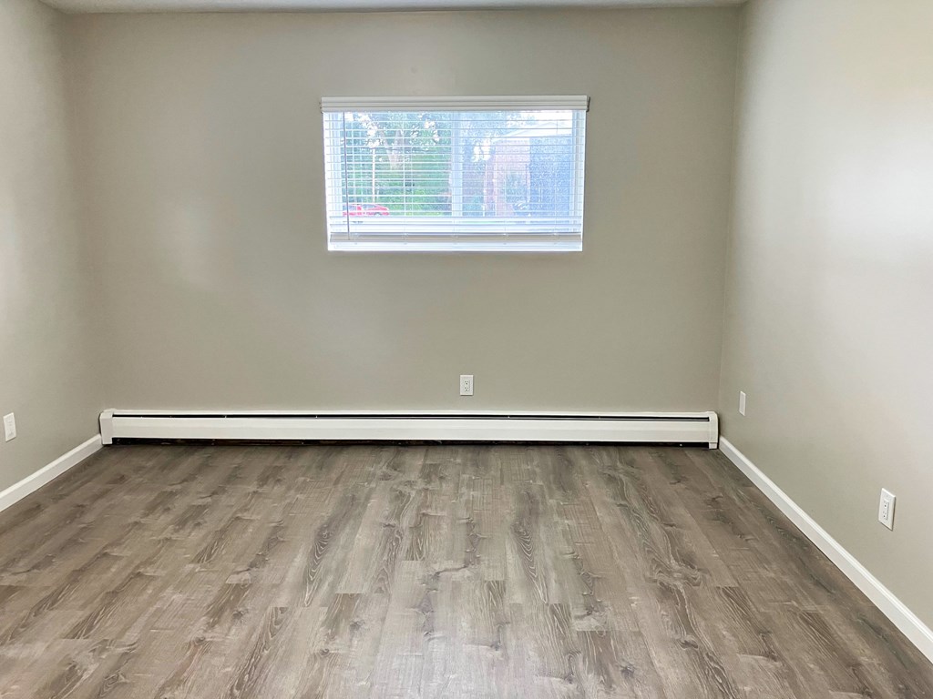 A room with a window and a wooden floor.