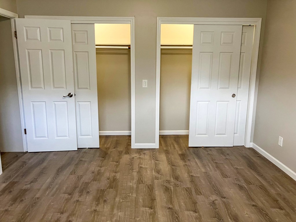A room with two white doors and wood flooring.