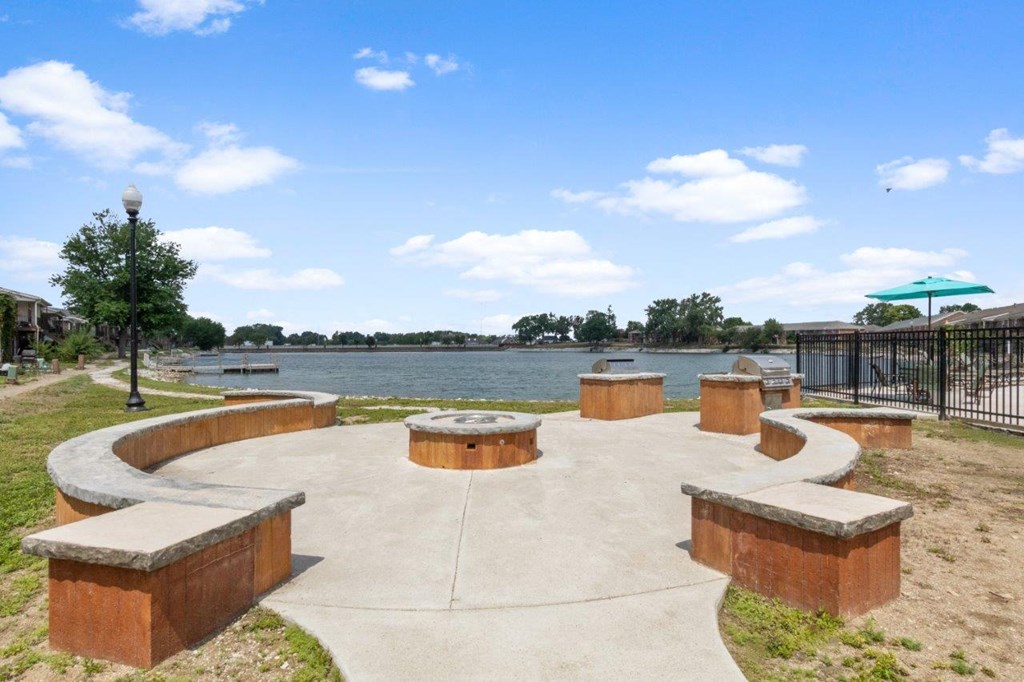 a gathering area with benches and tables near a body of water