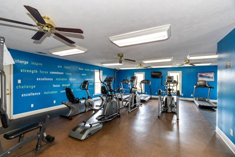 a gym with cardio machines and a ceiling fan