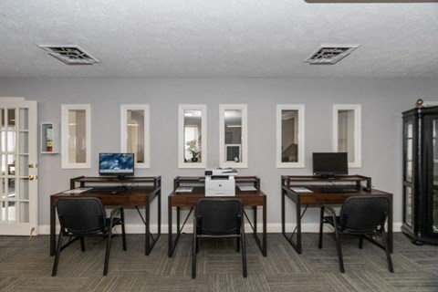 a conference room with desks and chairs and a laptop computer