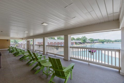 a porch with green chairs and a body of water