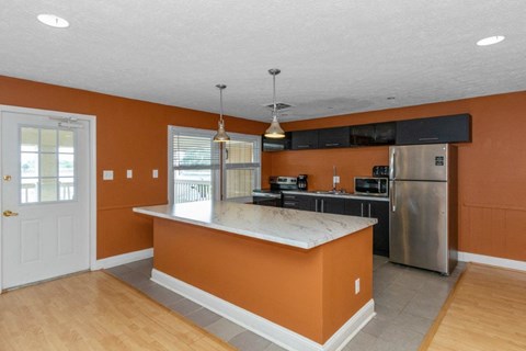 a kitchen with an island and a stainless steel refrigerator