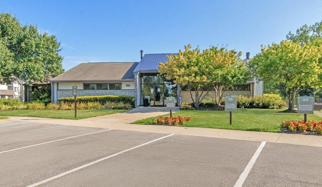 the front of the leasing office with a parking lot and trees