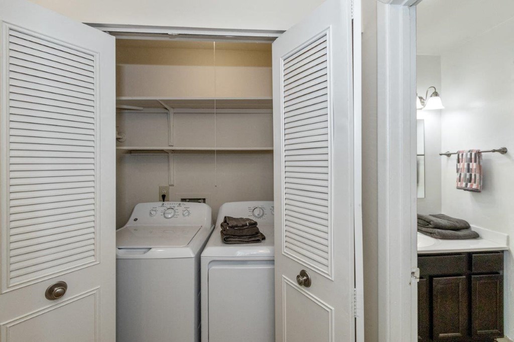 a laundry room with white appliances and white closet doors