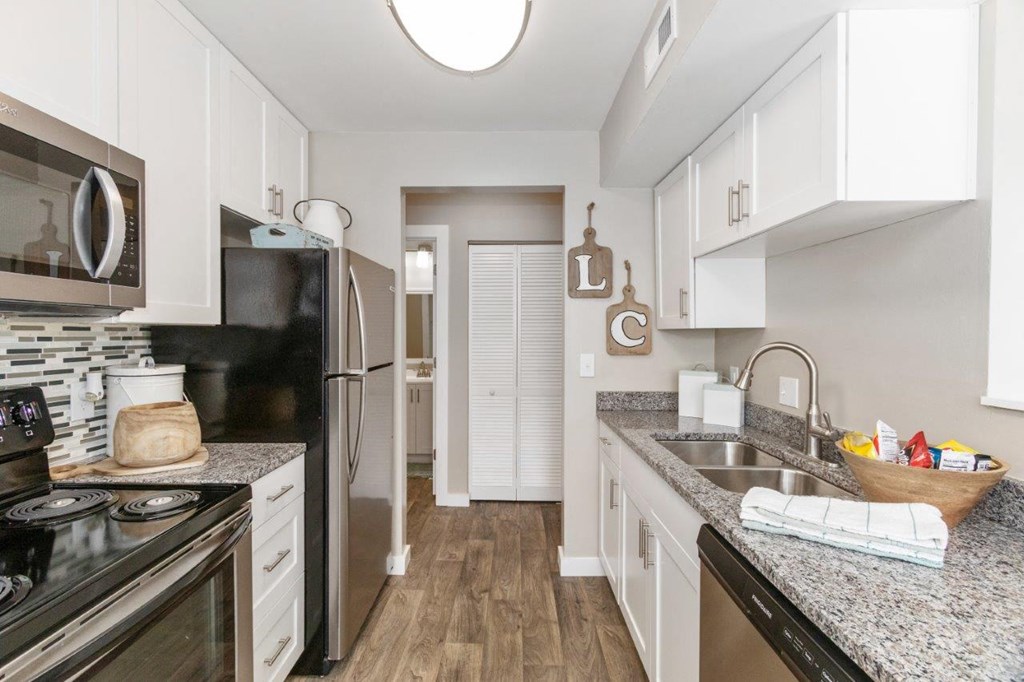 a kitchen with stainless steel appliances, modern white cabinets, and granite countertops