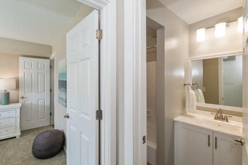 an attached bathroom with modern white cabinets and upgraded lighting
