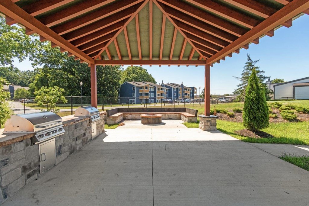 a covered patio with a grill and a fire pit