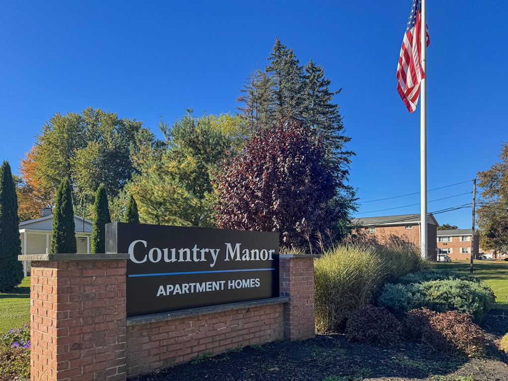 A sign that says Country Manor Apartment Homes in front of a building.