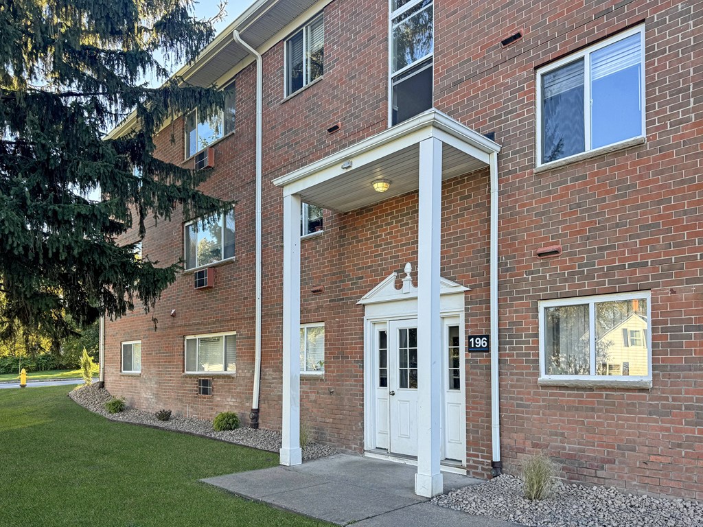 A red brick building with a white door and windows.