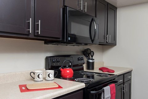 A kitchen with a black stove top and a black microwave above it.