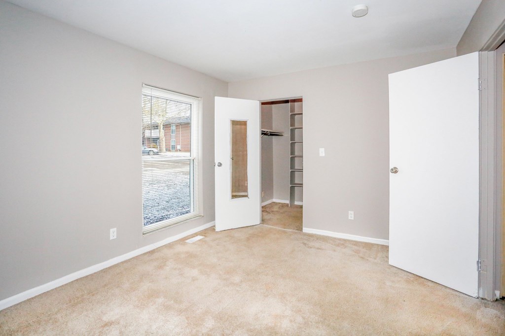 A room with a carpeted floor and a door leading to another room.