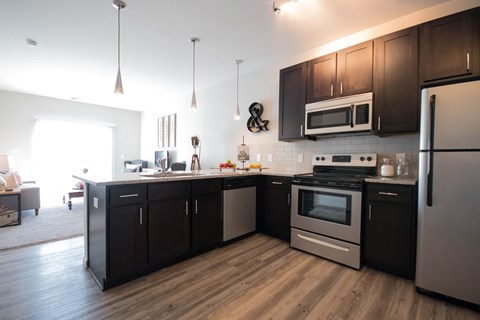 A modern kitchen with dark wood cabinets and stainless steel appliances.