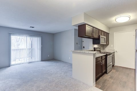 A kitchen with white cabinets and a window with white blinds.