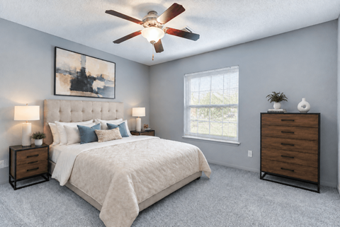 A bedroom with a large bed, a ceiling fan, and a window.