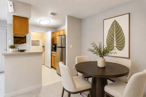 A dining room with a table and chairs and a leafy plant on the table.