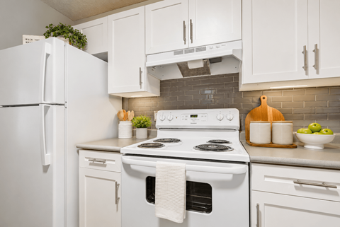 A white stove with a white oven and a white refrigerator in a kitchen.