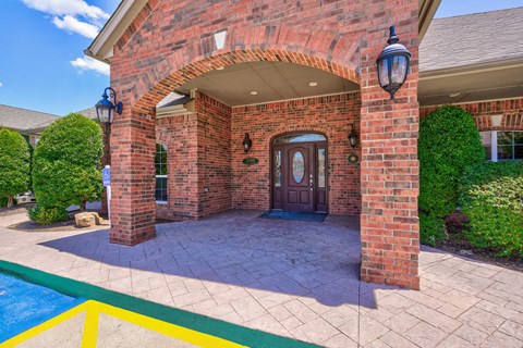 A red brick house with a pool in front.