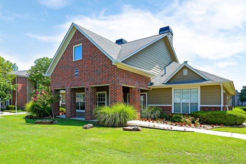A red brick house with a green lawn in front.