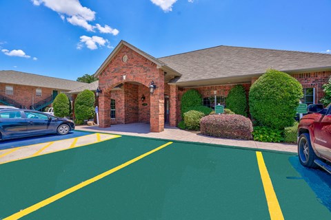 A parking lot with a building and cars parked in front.
