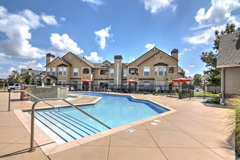 A swimming pool surrounded by a concrete patio and a metal railing.