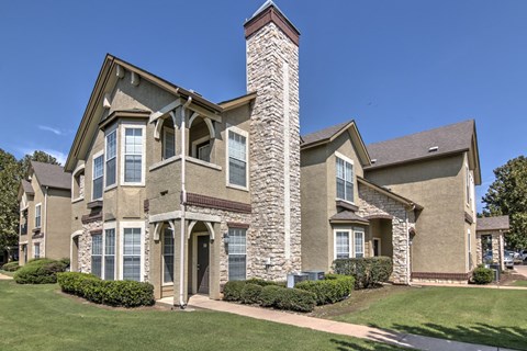 A large house with a stone chimney and a brown roof.