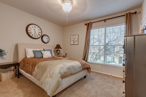 A bedroom with a large bed and two clocks on the wall.