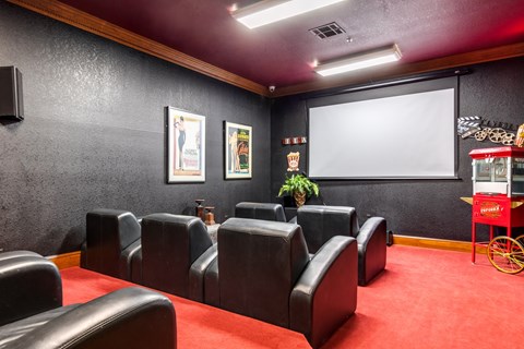 A movie theater with red carpeting and black leather chairs.