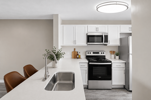 A modern kitchen with white cabinets and appliances.