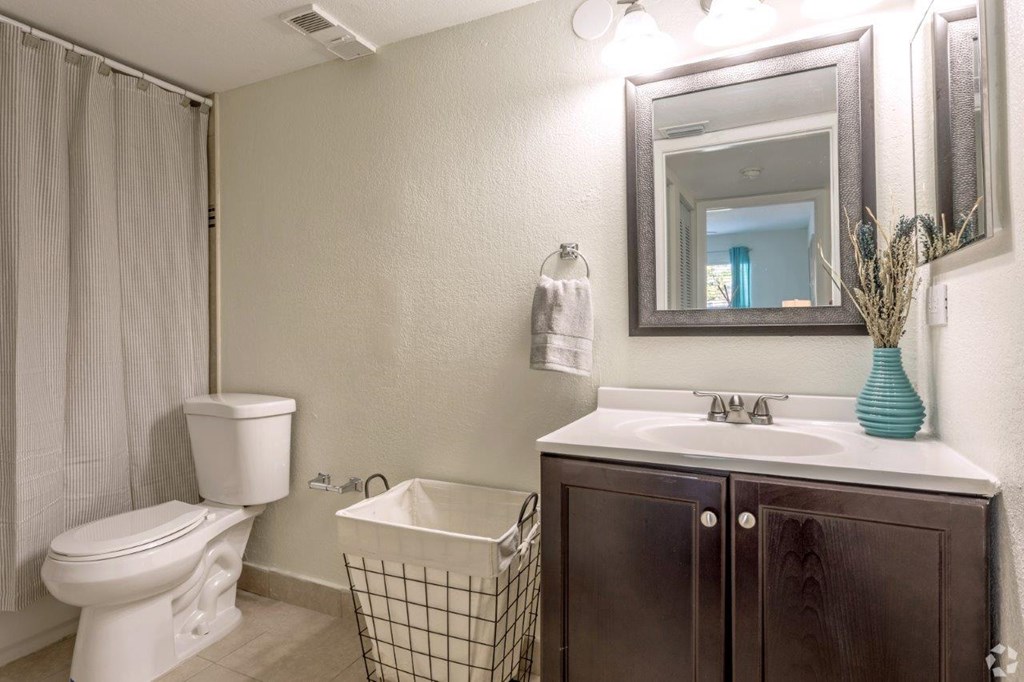 A bathroom with a white toilet, a white sink, and a brown cabinet.