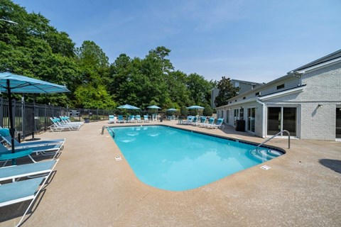 A large outdoor swimming pool surrounded by lounge chairs and umbrellas.