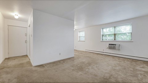 a living room with white walls and carpet and a window
