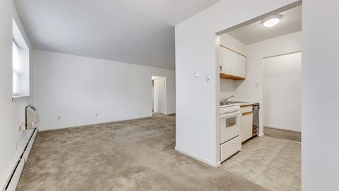 an empty living room and kitchen with a stove and refrigerator