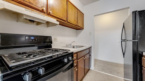 A black stove top oven sits in a kitchen with wooden cabinets.