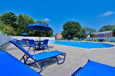 A pool area with blue chairs and umbrellas.