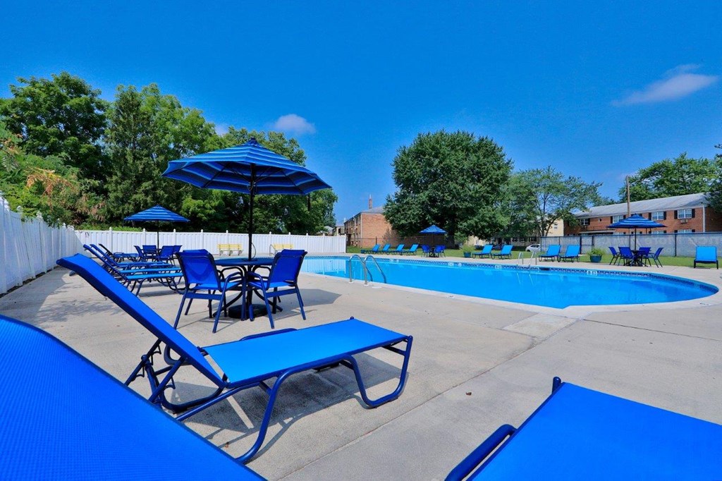 A pool area with blue chairs and umbrellas.