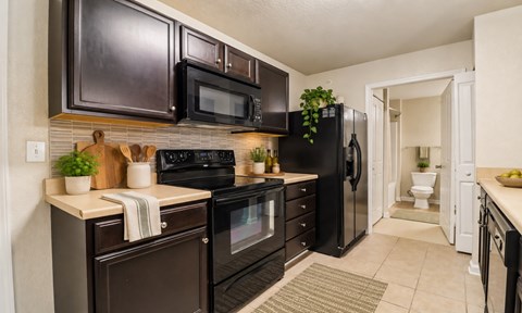 A kitchen with black appliances and brown cabinets.