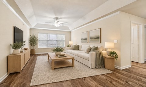 A living room with a white couch, a wooden coffee table, and a flat-screen TV mounted on the wall.