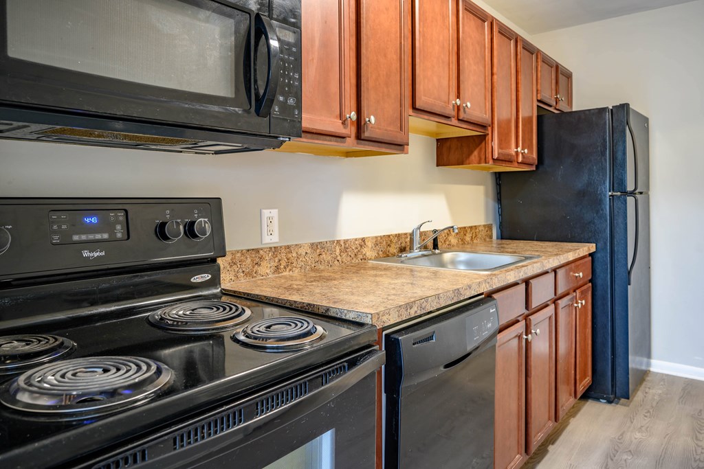 A kitchen with black appliances and wooden cabinets.