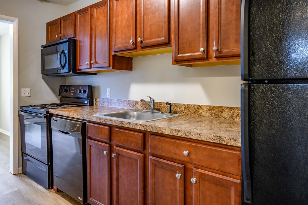 A kitchen with black appliances and brown cabinets.