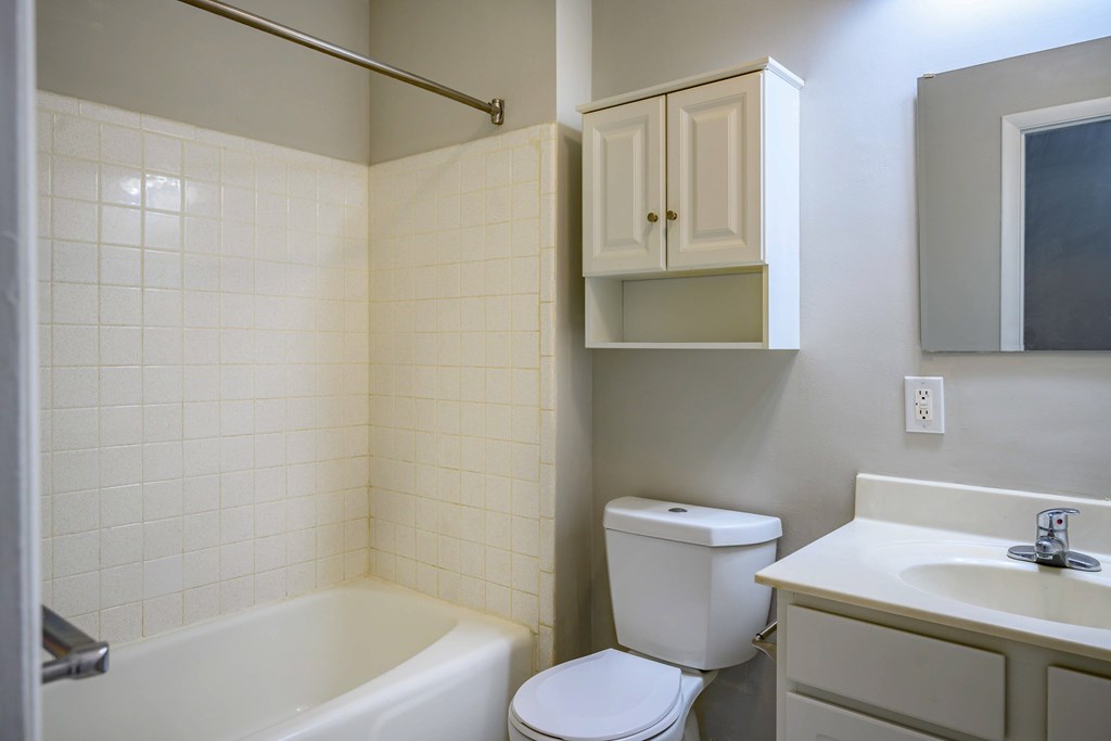 A white toilet sits next to a white bathtub in a bathroom.