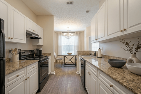 A kitchen with white cabinets and a black stove top oven.