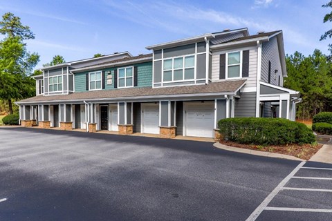 a large gray house with white columns and a parking lot
