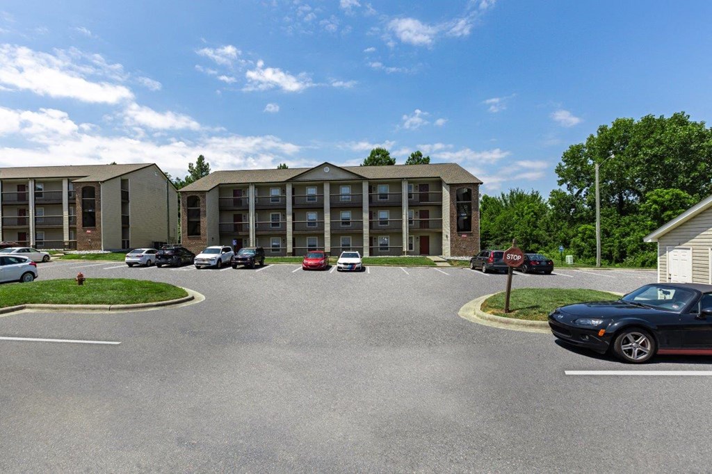 a parking lot with cars in front of an apartment building