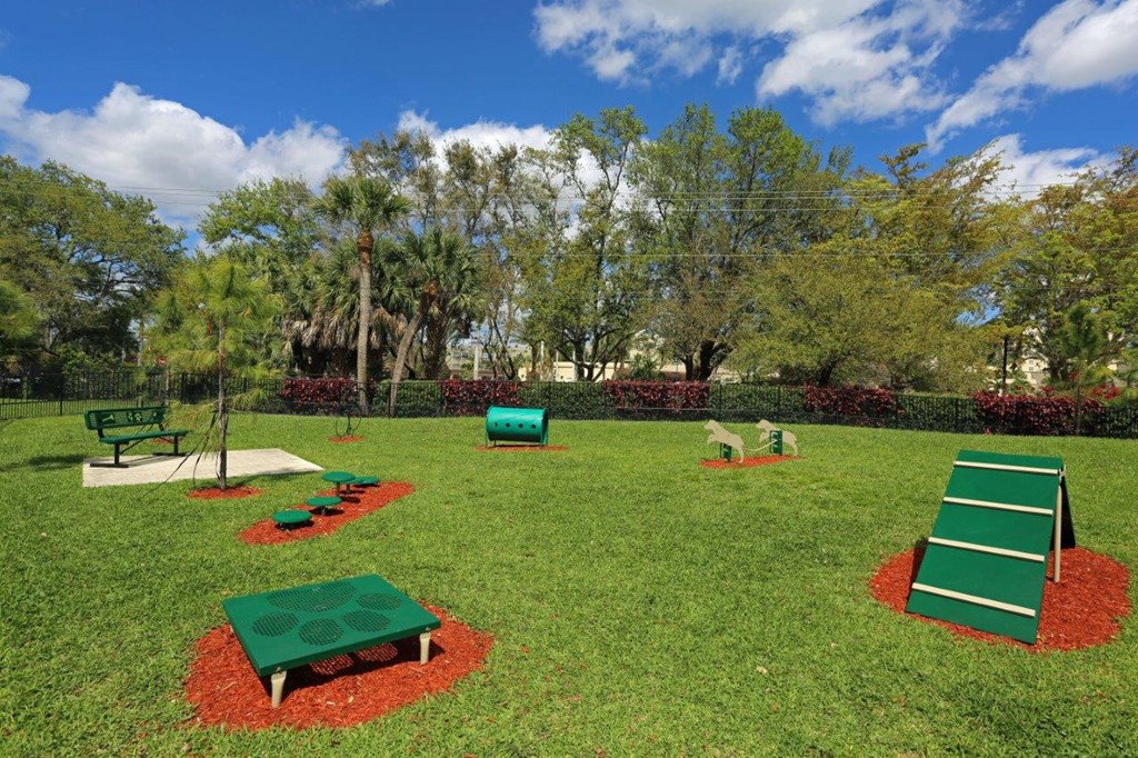 A park with a green lawn and a red flower bed.