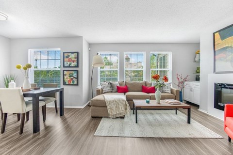 A living room with a couch, coffee table, and a dining table.