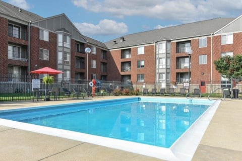 A swimming pool in front of a brick apartment building.