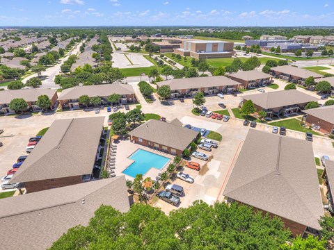 A bird's eye view of a residential area with houses, a swimming pool, and a parking lot.