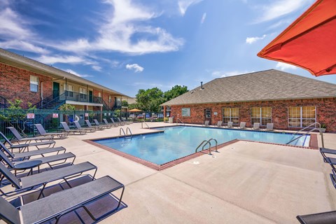A pool surrounded by lounge chairs and umbrellas.
