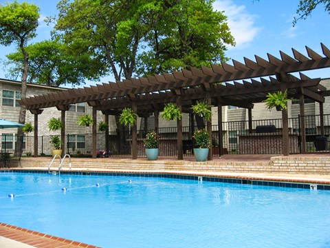 A pool with a wooden pergola over it.